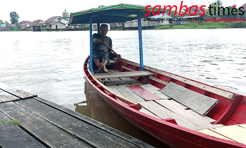 Muhammad Arif Ismail menunggu penumpang menaiki perahu tambangnya di dermaga Pasar Sambas, Senin (26/07/2022) 
