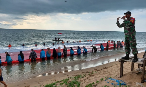 Pembentangan Bendera Merah Putih di Pantai Temajuk pada kegiatan Aksi Sosial Merah Putih, Sabtu (13/8/2022)
